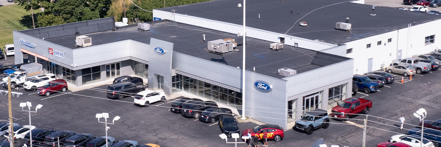 Dealership employee smiling shaking hands with satisfied customer.