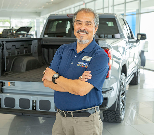 Spanish speaking employee standing in front of a car
