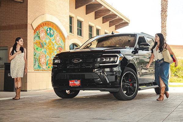 Two girls walking beside a new ford SUV