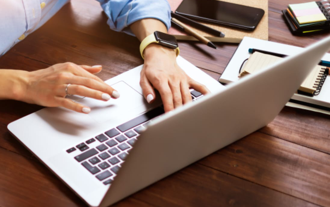 A woman’s hands typing on a laptop. 