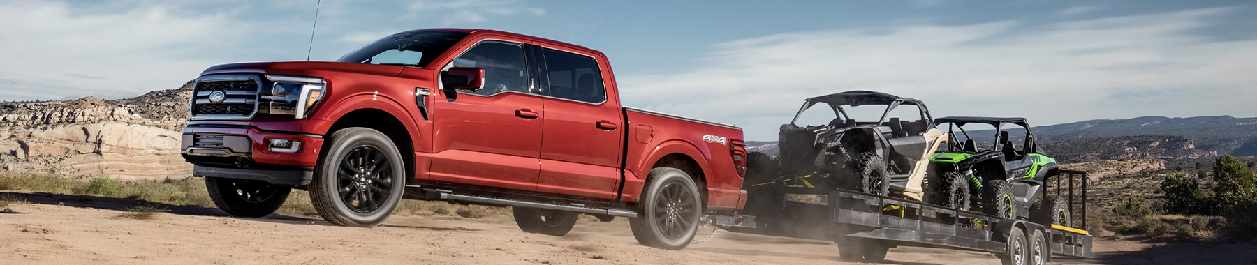 2024 Ford F-150® pickup in Rapid Red pulling a trailer loaded with ATVs