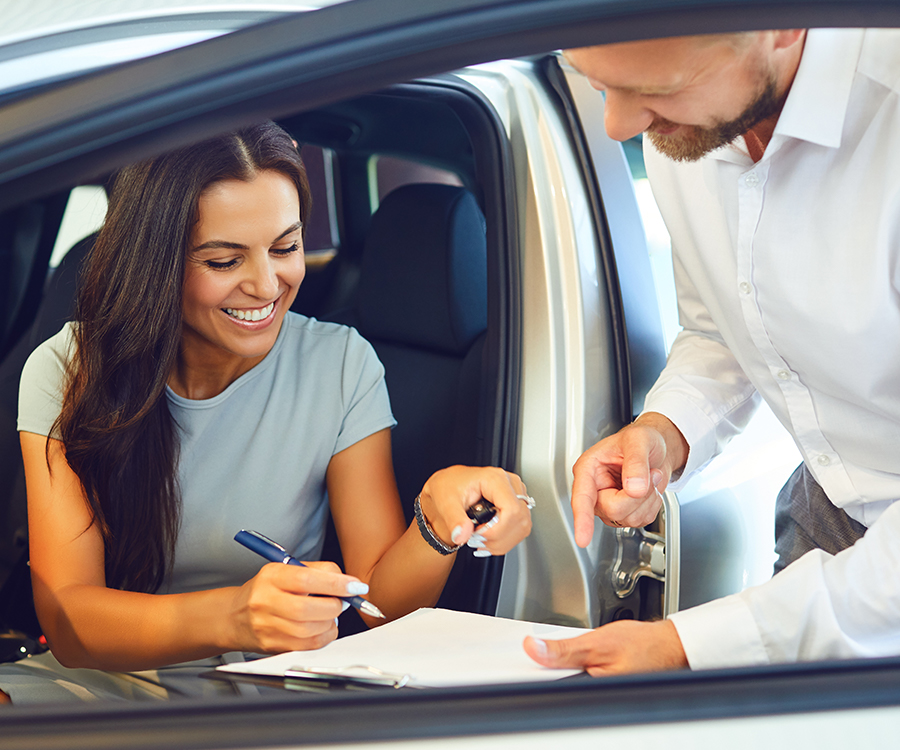 A young woman buys a car in a car showroom.