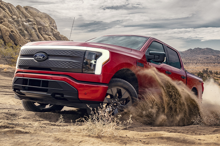 A 2024 Ford F-150 Lightning® being driven on a forested trail