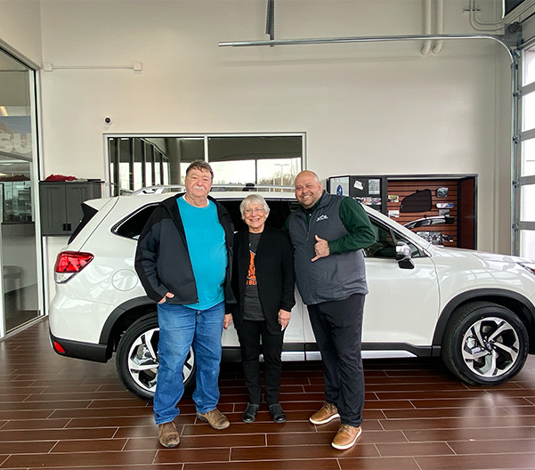 people standing outside the dealership with their new car