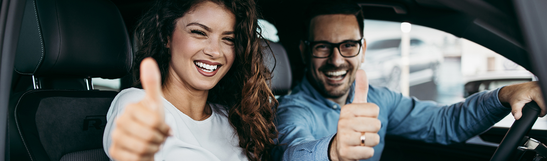 Happy middle age couple enjoying while choosing and buying new car at showroom.