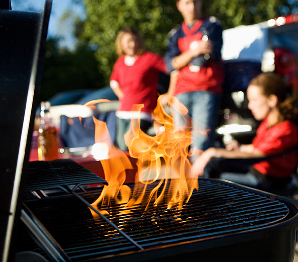Close up on a grill while people are tailgating.
