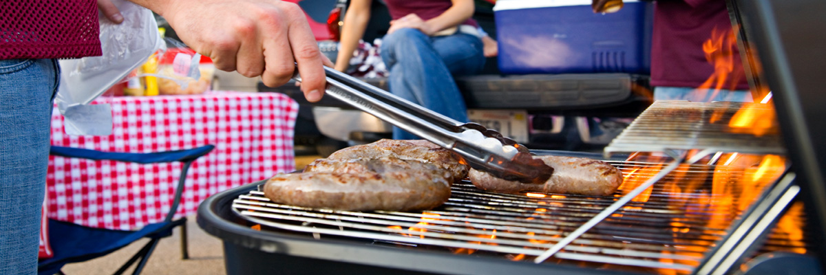 Close up on a grill while people are tailgating.
