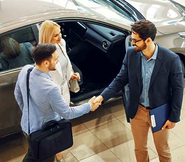 Car salesman shaking hands with customers in a dealership