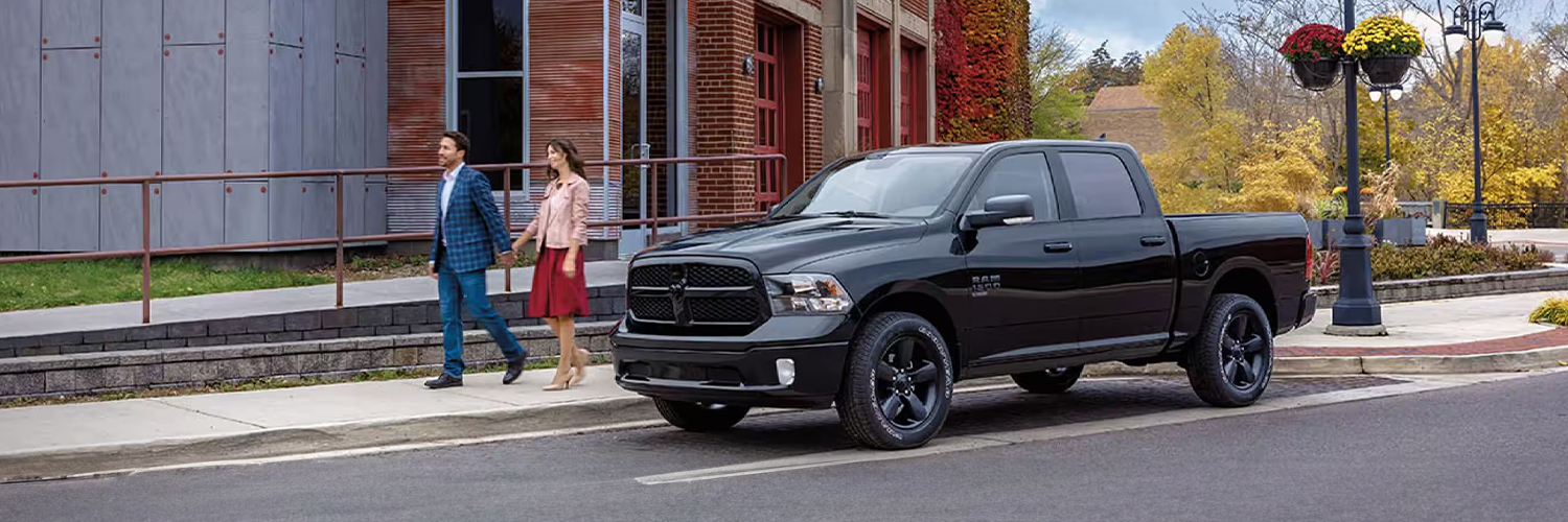 A black 2024 Ram 1500 Classic Tradesman Crew Cab parked next to a fire station.