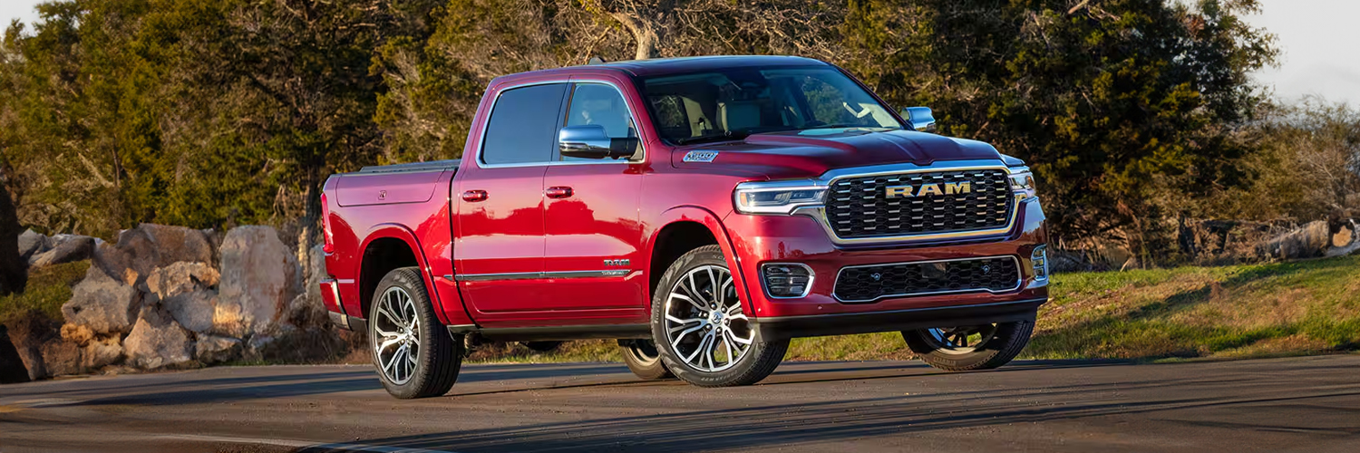 A red 2025 Ram 1500 Tungsten Crew Cab being driven on a highway.